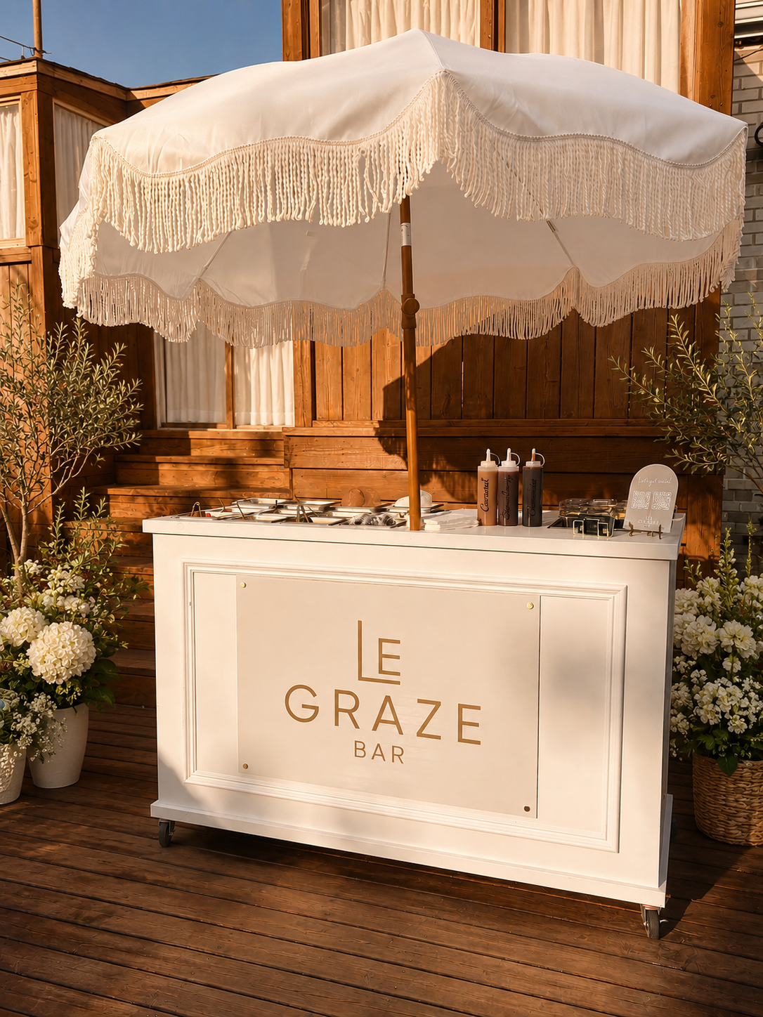 Le Graze Bar cake bar cart with fringed parasol and gold logo