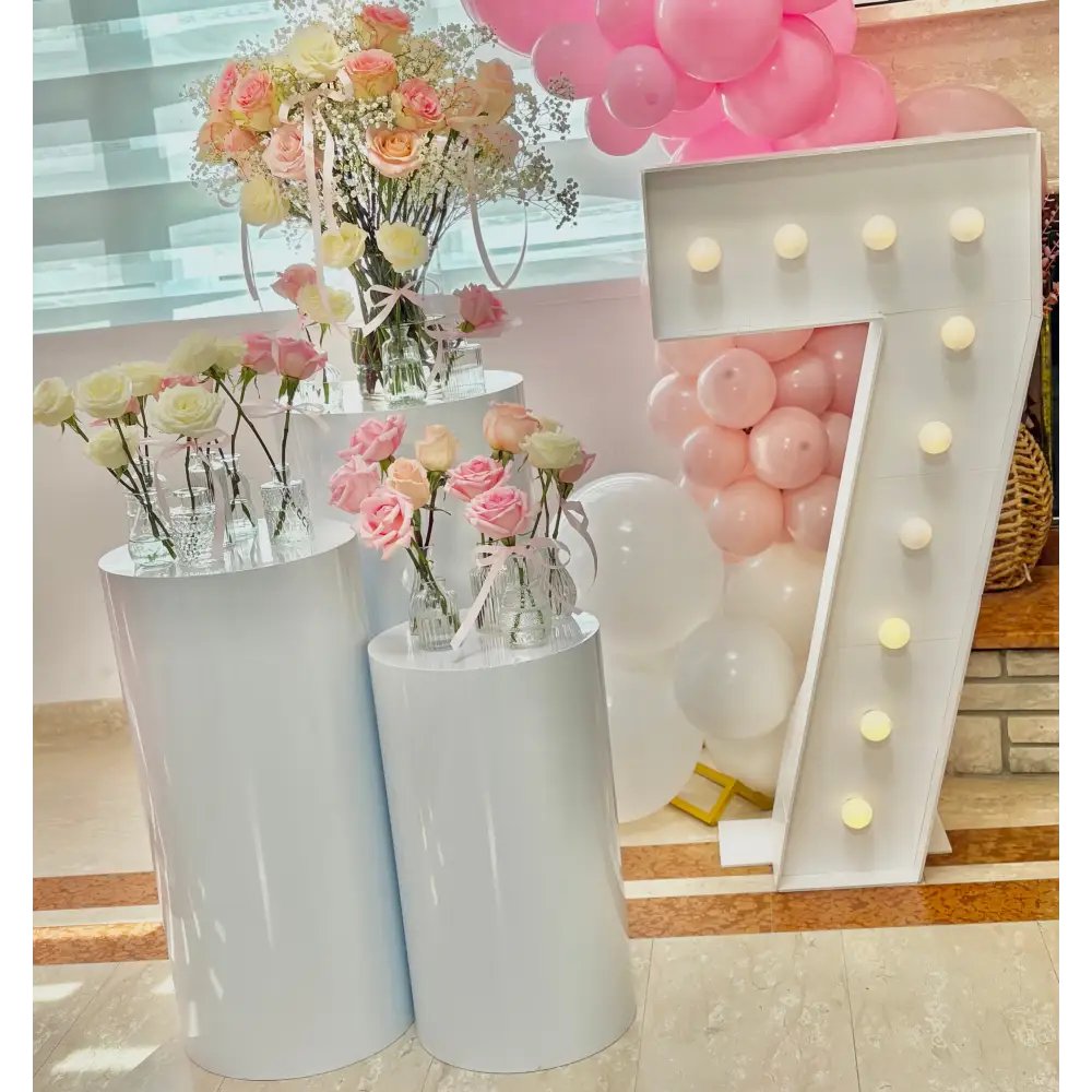 White cylinder pedestals with florals and marquee number